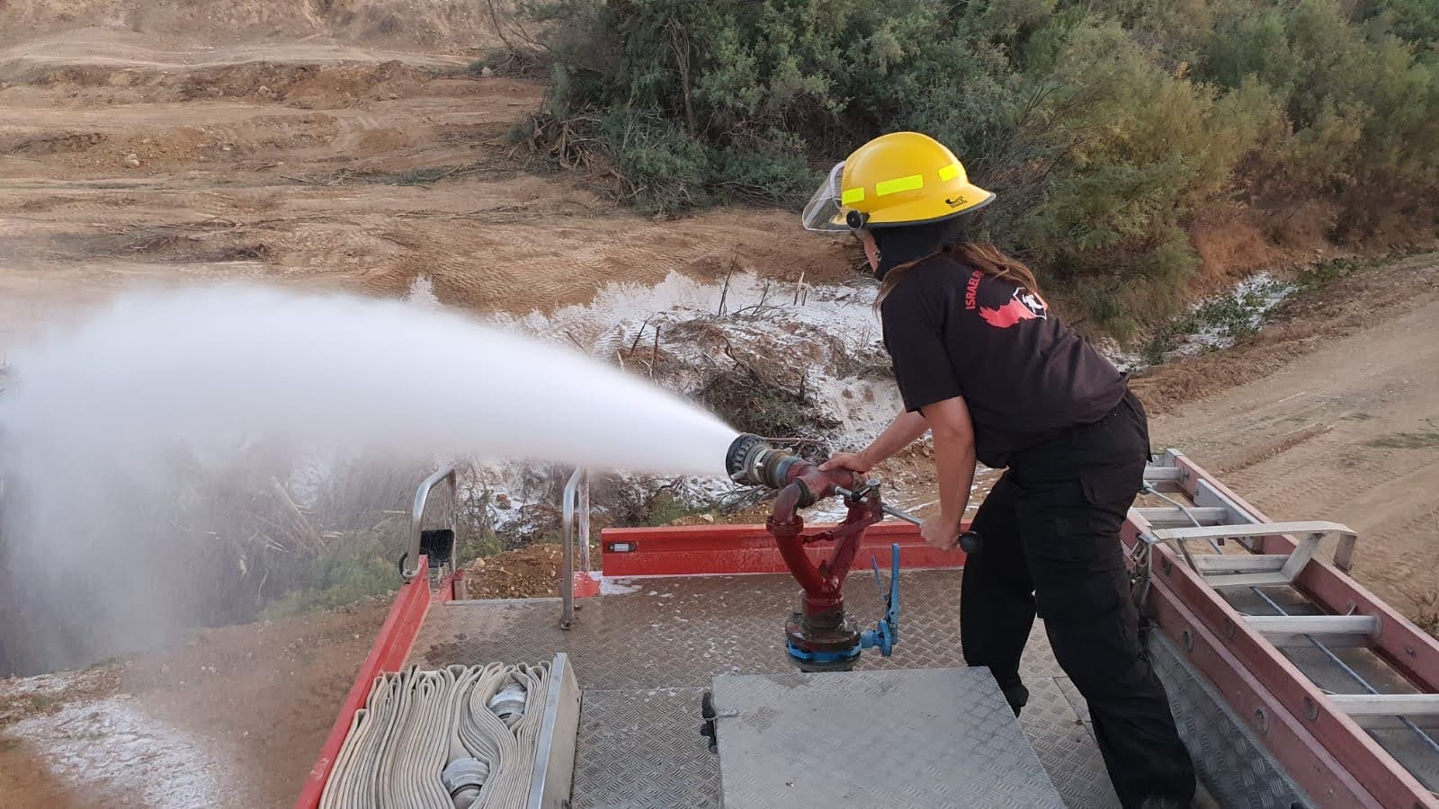 Gal Noy operates a fogtip nozzle from the hosebed of a fire engine