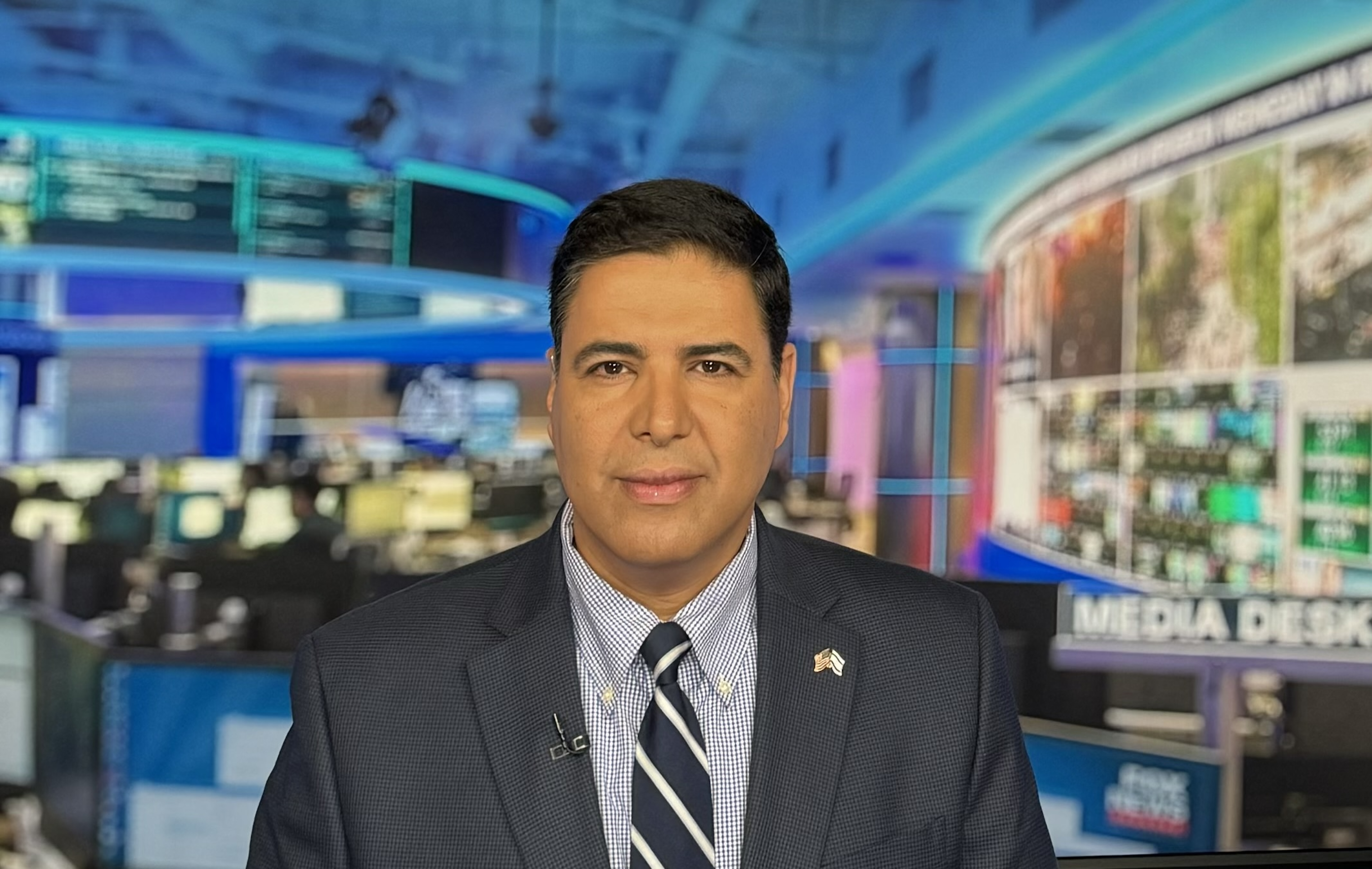 Shahar Azani appears in a television news studio wearing a suit and tie.