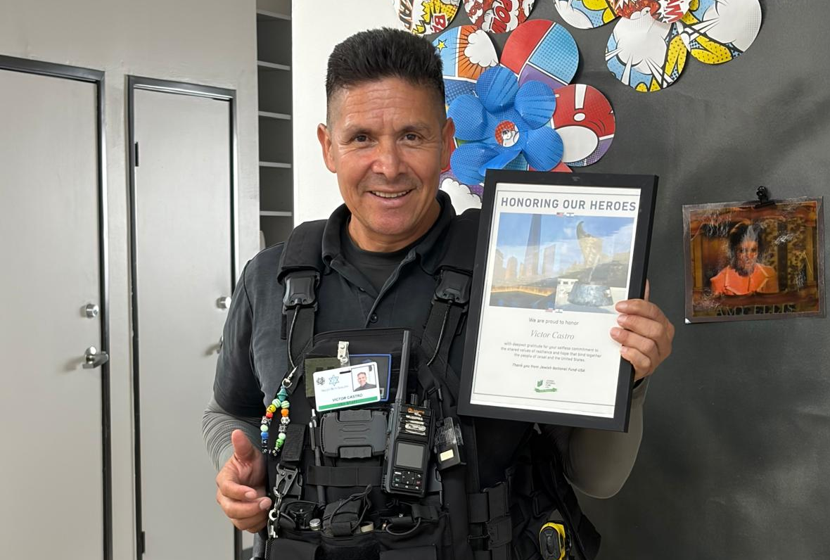 Security guard Victor Castro giving a thumbs up and holding the certificate of appreciation