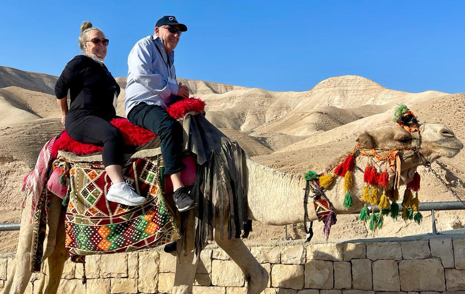 two people riding a camel in the desert